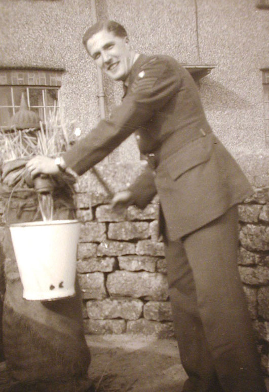 Sandy Munro using the pump outside Spinners Cottages